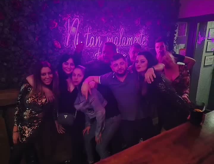 Grupo de amigos posando frente al neón del bar